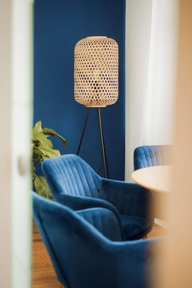 Blick durch die Tür auf zwei blaue Sessel und eine Stehlampe