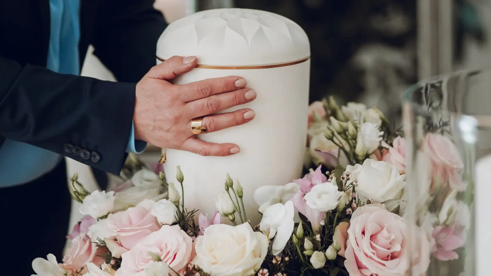 Hand auf einer Urne mit Blumen