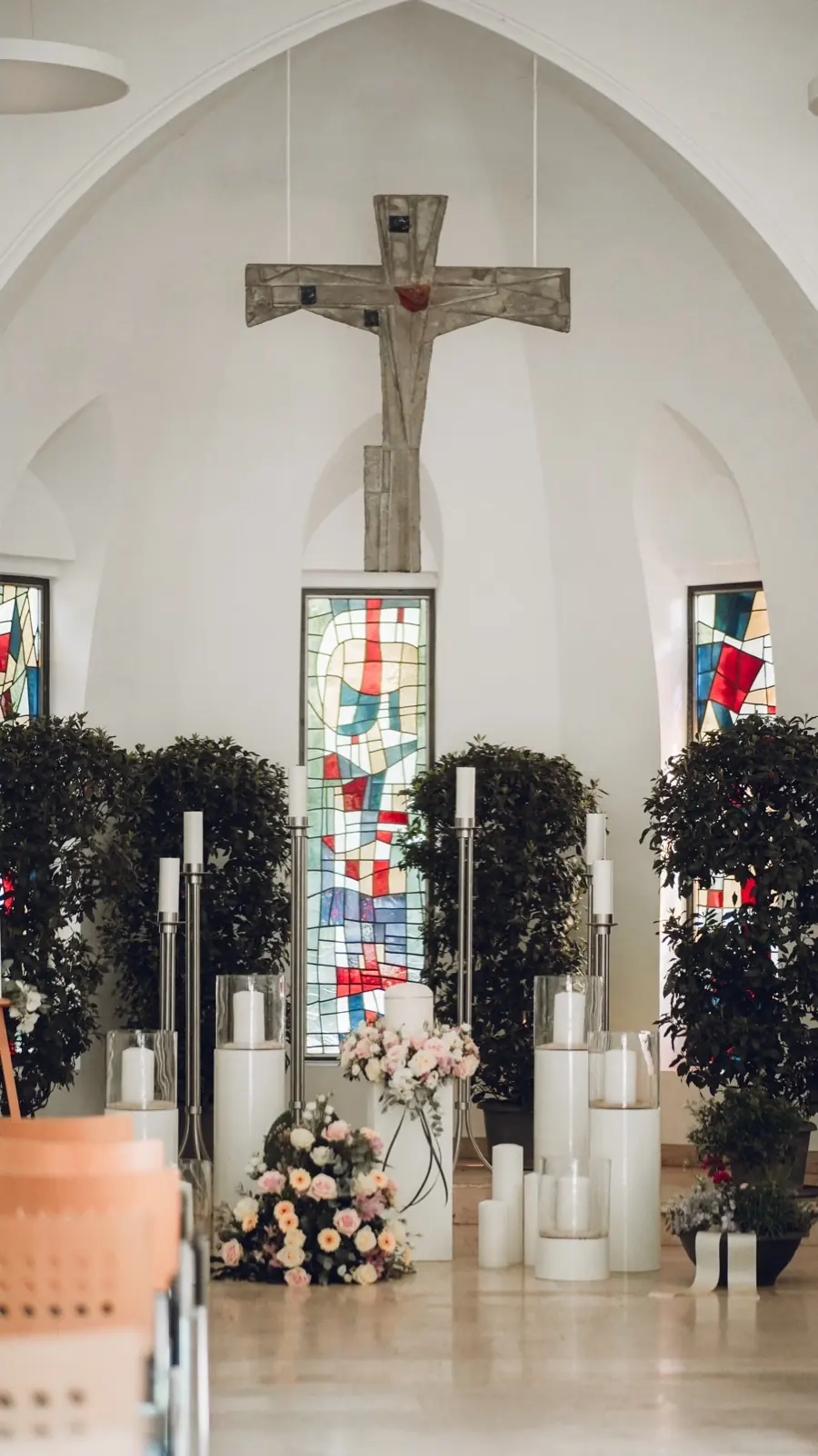 Trauerhalle mit Holzkreuz, Kerzen und Blumenschmuck